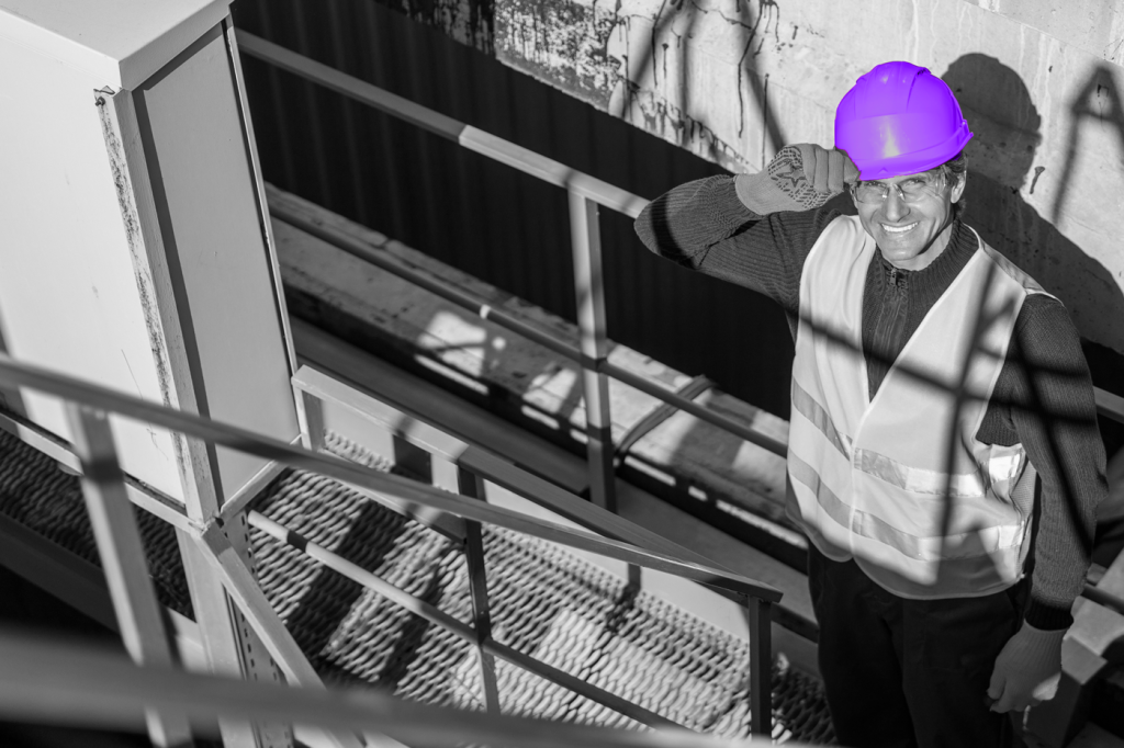 Elevator mechanic in hard hat and safety vest, addressing technician shortage in elevator service.